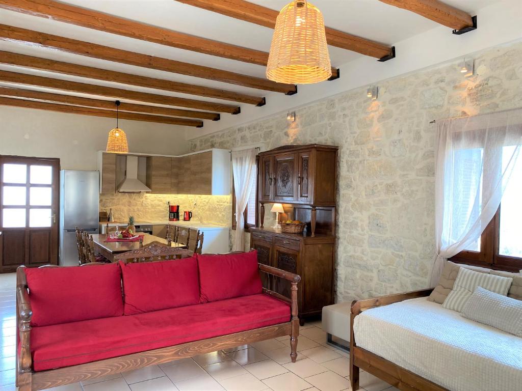 a living room with a red couch and a kitchen at Malvazia Residence in Kamilari