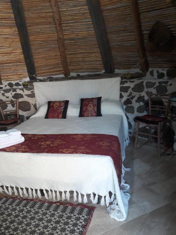 Un dormitorio con una cama blanca con almohadas. en Ovile Juanne Loddo, en Orosei