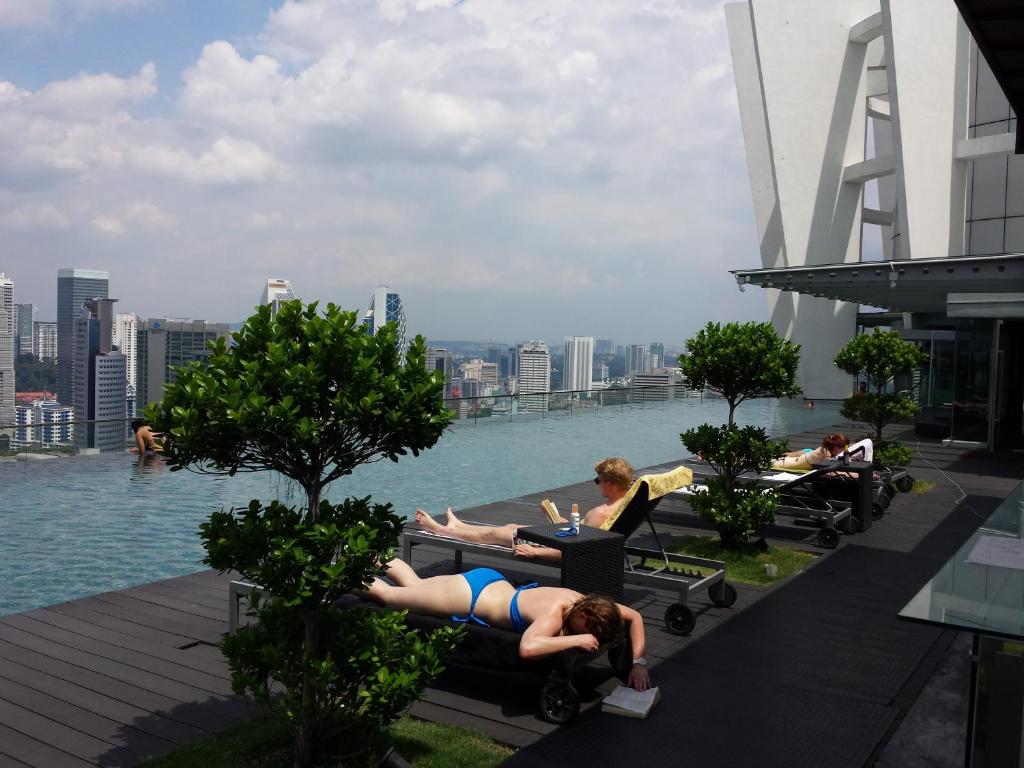 a group of people laying on tables next to the water at BEST KL City View at Regalia Residence in Kuala Lumpur