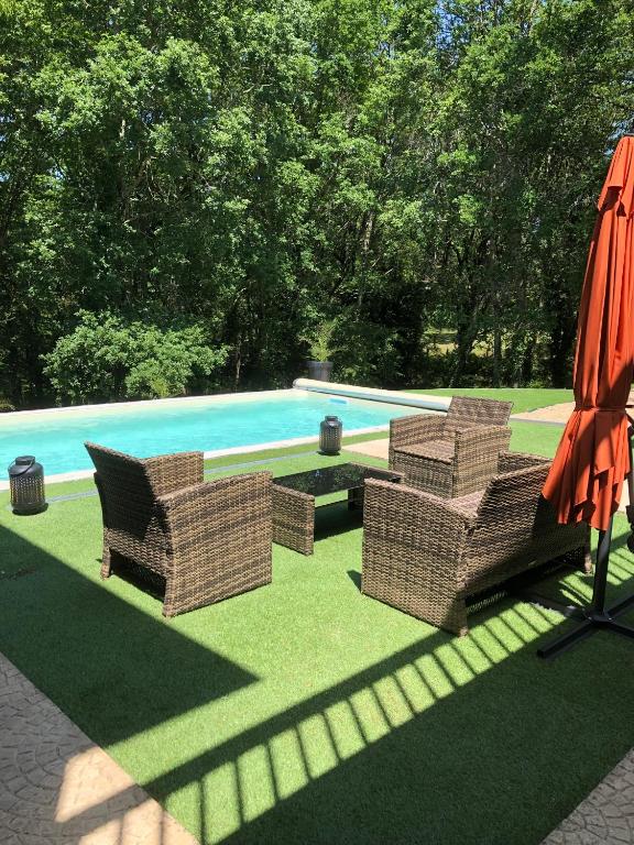 deux chaises et un parasol à côté d'une piscine dans l'établissement Charmant Petit gite au milieu de la Verdure, à Coulounieix-Chamiers