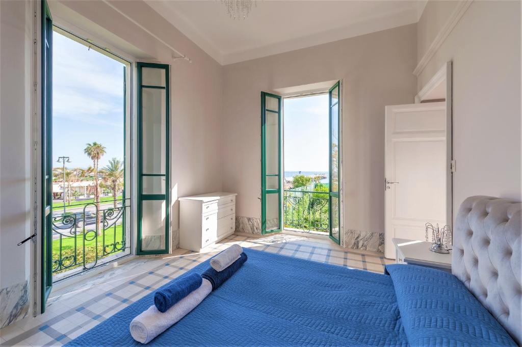 a bedroom with a blue bed and large windows at [- Poetic Seafront Penthouse Versilia -] in Massa