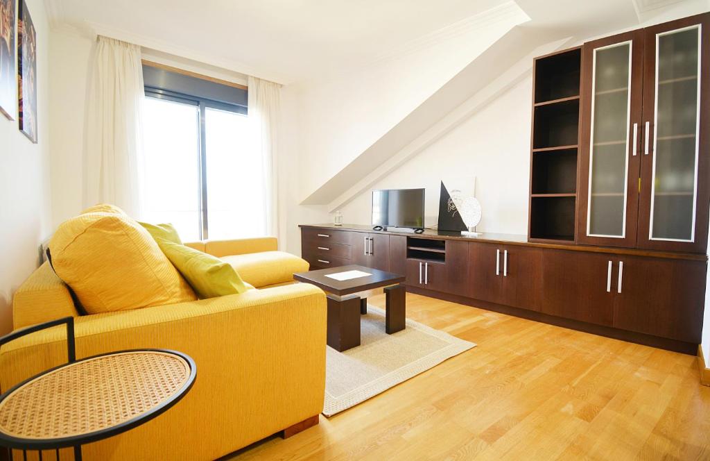 sala de estar con sofá amarillo y mesa en Céntrico apartamento con parking en Cambados, en Cambados