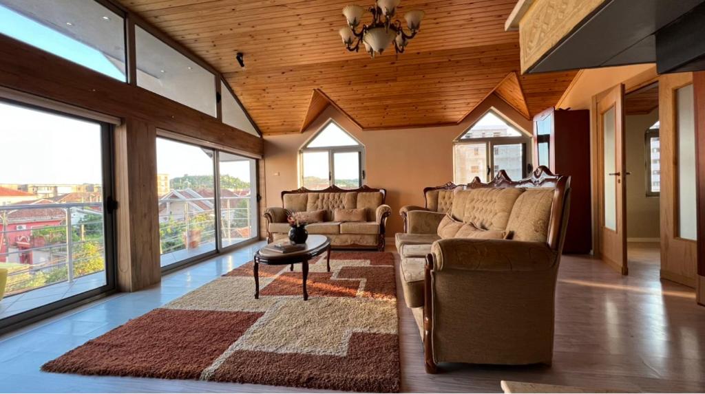 - un salon avec des canapés, une table et des fenêtres dans l'établissement Ora Apartment, à Shkodër