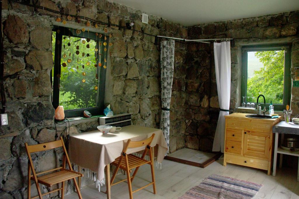 uma cozinha com uma mesa e cadeiras e uma parede de pedra em Zove Rural Cottage with garden views em Kʼarashamb