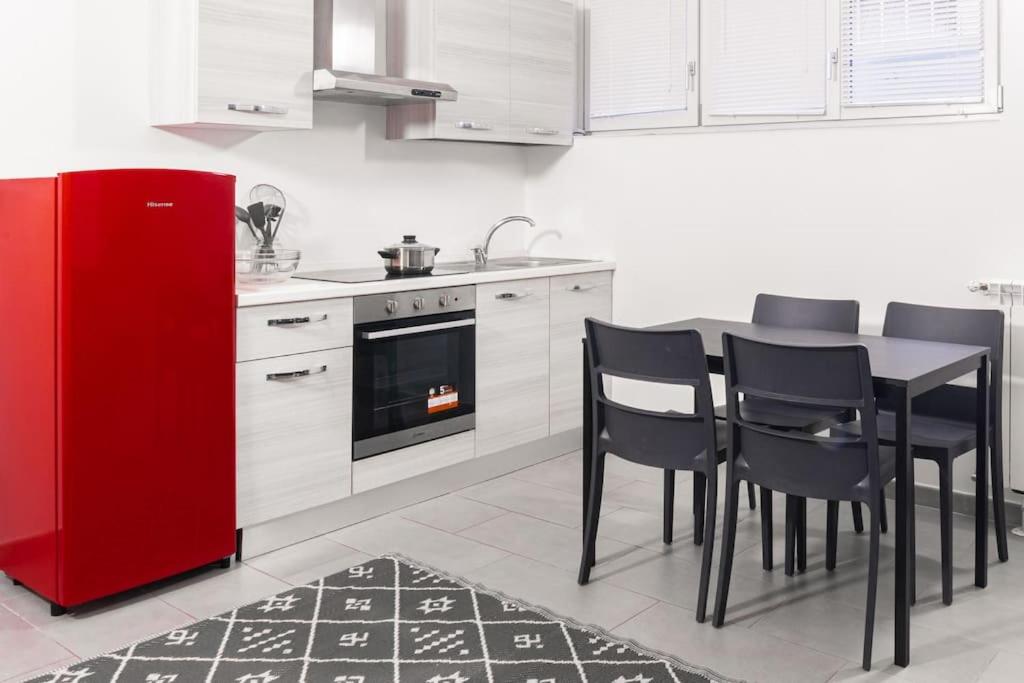 a kitchen with a red refrigerator and a table and chairs at Staurenghi Green Apartment in Varese