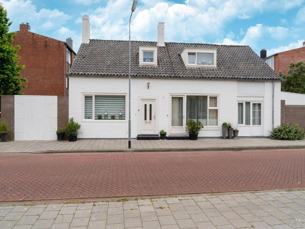 una casa blanca sentada en una calle de ladrillo en Comfortable semi-detached holiday home in Vlissingen, en Vlissingen