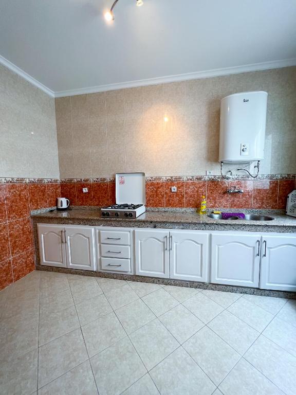 a kitchen with white cabinets and a counter top at Rif Appartment in Al Hoceïma