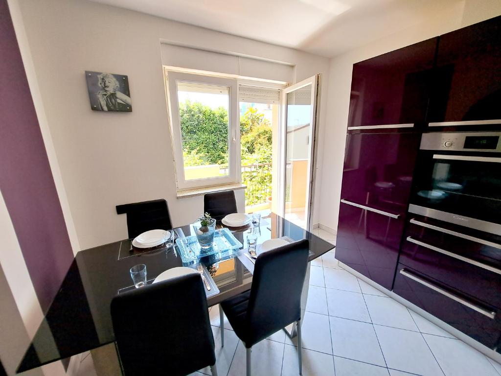 a dining room with a glass table and black chairs at Apartman Koli Opatija in Opatija