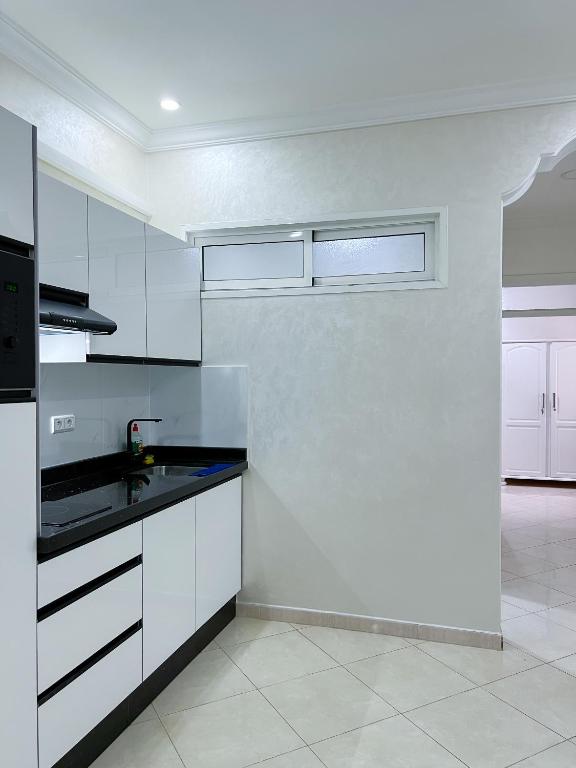 a kitchen with white cabinets and a black counter top at Rif Appartment in Al Hoceïma