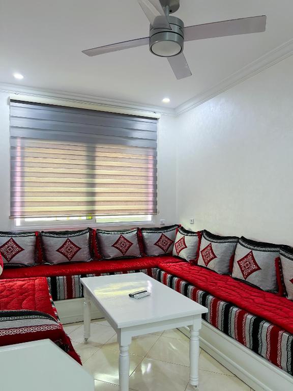 a living room with a red couch and a table at Rif Appartment in Al Hoceïma