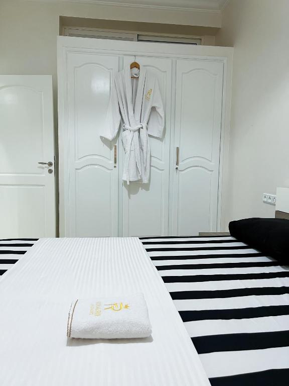 a white bed with a robe hanging on a door at Rif Appartment in Al Hoceïma