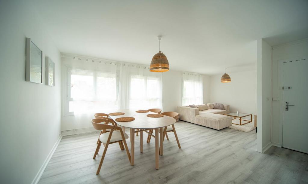 una sala de estar blanca con mesa y sillas en La vie en Beige - Appartement à Chalon-sur-Saône, en Chalon-sur-Saône