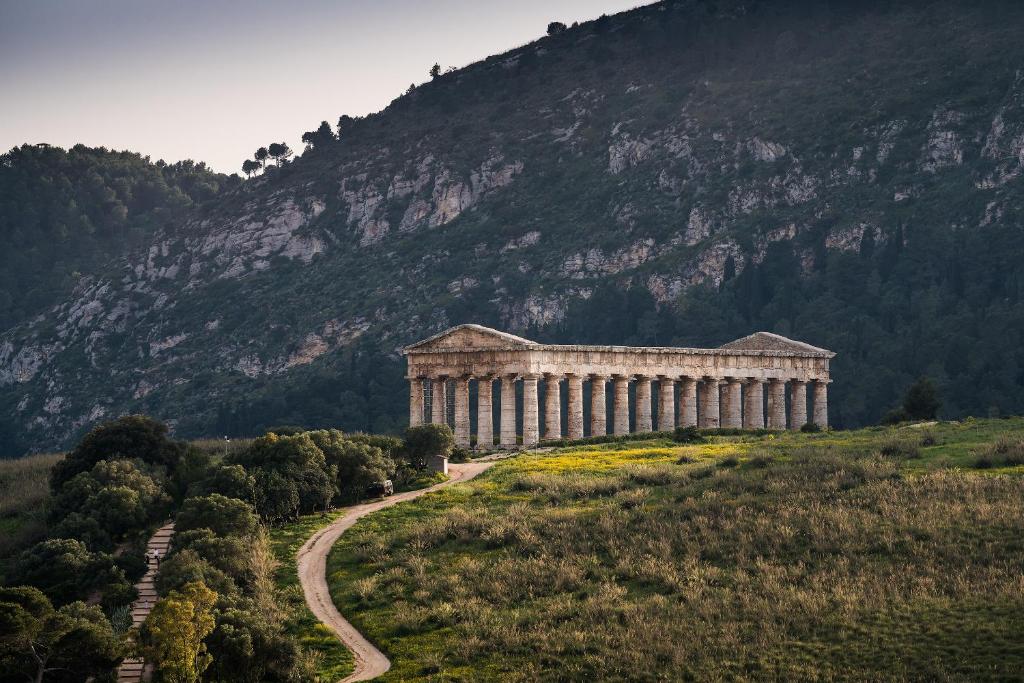 un edificio en una colina junto a una montaña en Helimos Bed&Breakfast Segesta Temple-Castellammare, en Calatafimi