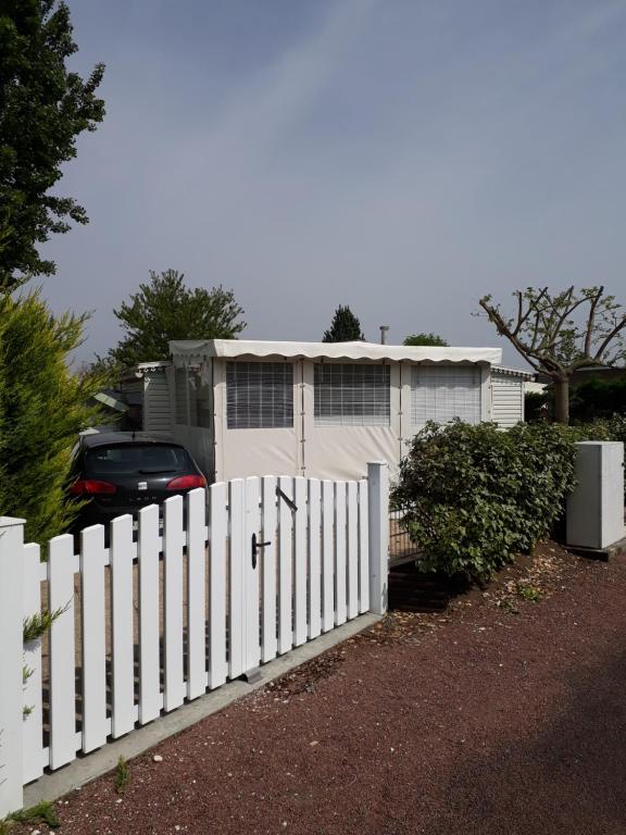 una recinzione bianca di fronte a una casa con un'auto di Marennes mobilhome 46 Domaine des pins a Marennes