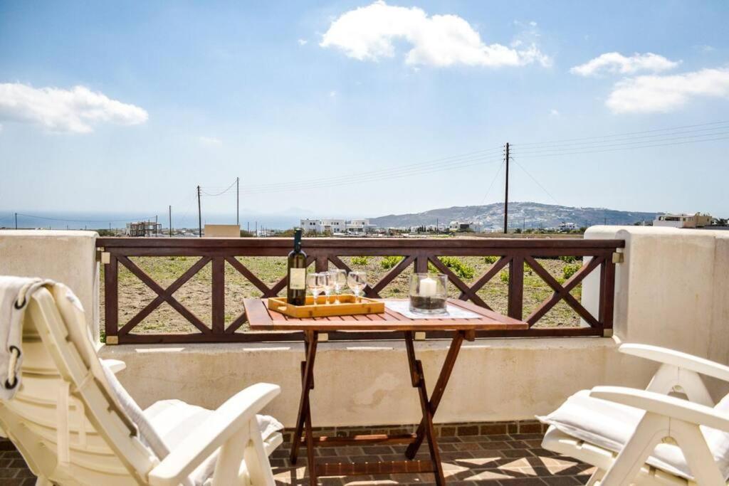 a table and chairs on a balcony with a bottle of wine at Το Μεγάλο Αμπέλι in Megalokhori