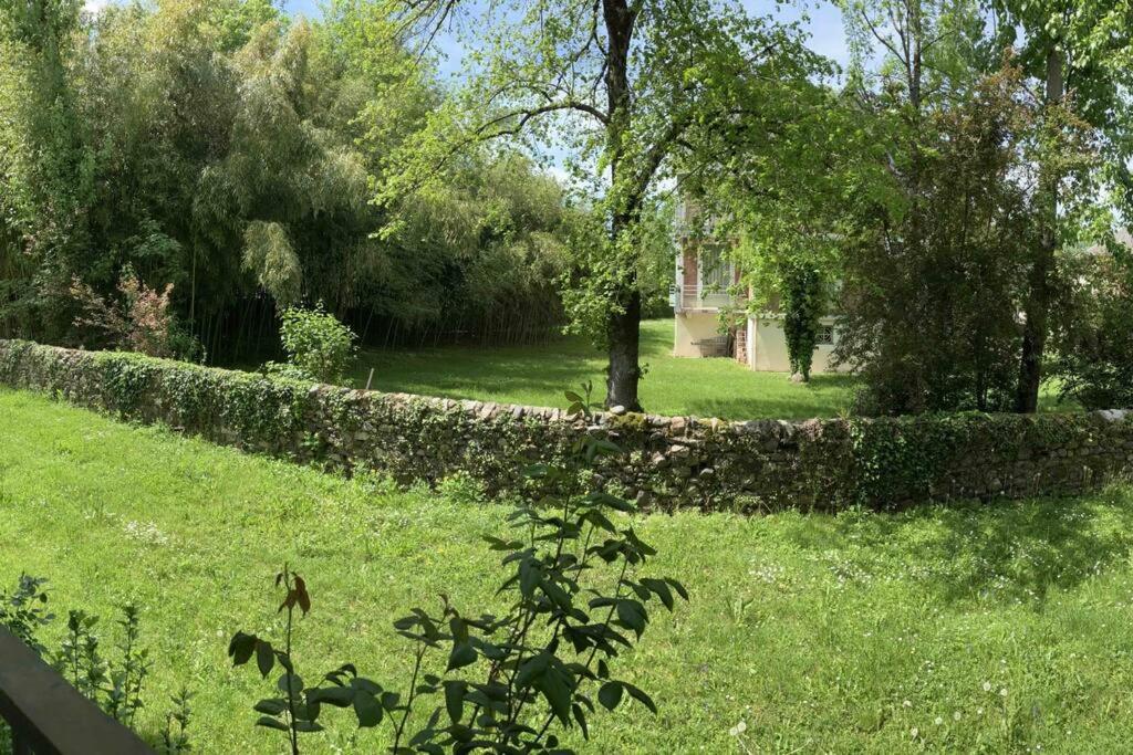 a stone fence in a yard with grass and trees at Studio centre-ville au calme in Espalion
