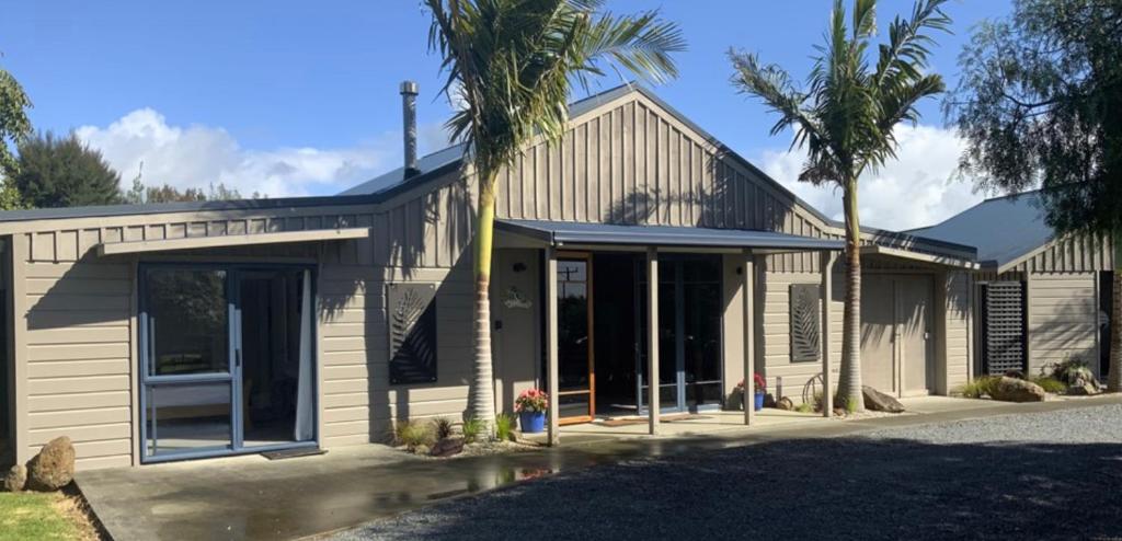 a building with palm trees in front of it at A Cut Above Lodge - The Gateway to the Bay of Islands in Kerikeri