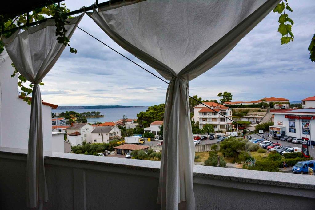 uma vista para a cidade a partir de uma varanda com cortinas em Apartment in Banjol/Insel Rab 26609 em Banjol