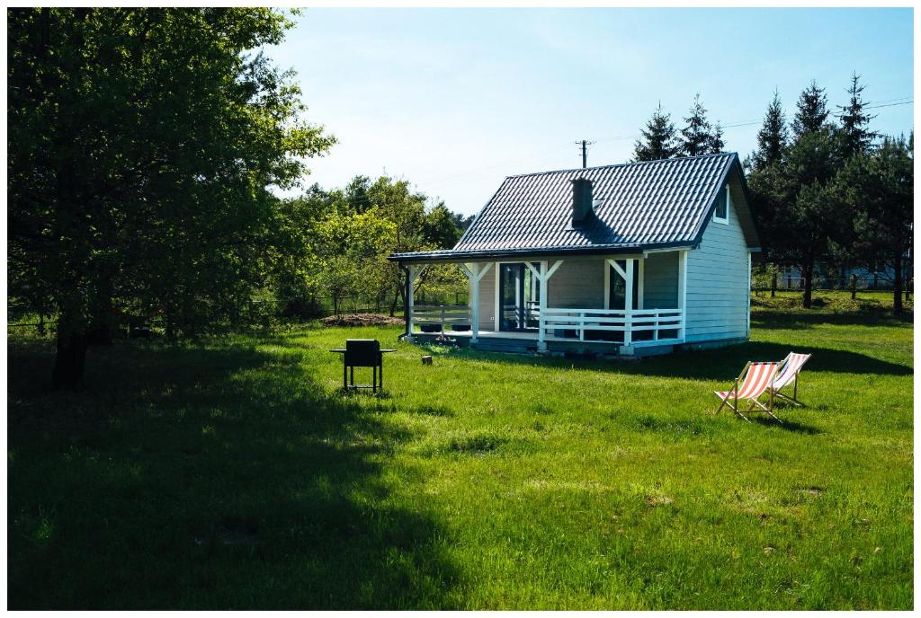 een klein blauw huis met twee stoelen in een veld bij Enklava in Szramowo