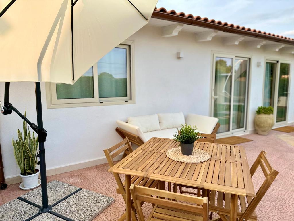 eine Terrasse mit einem Tisch, Stühlen und einem Sonnenschirm in der Unterkunft Maison Céline in Syrakus