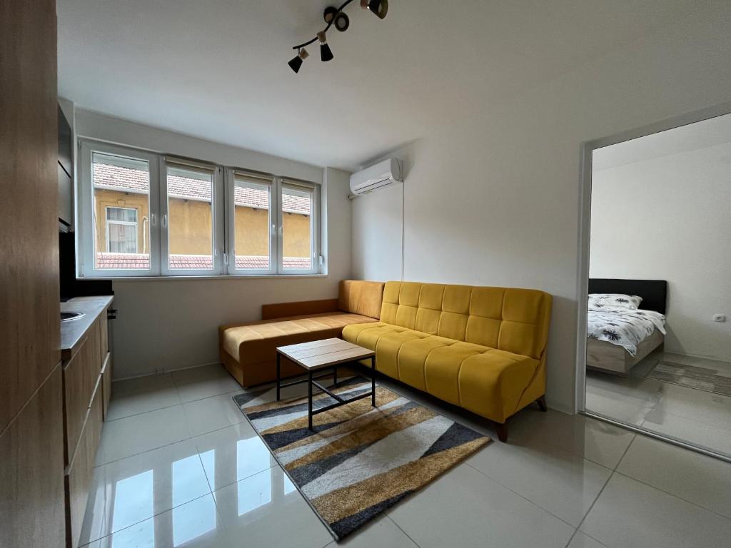 a living room with a yellow couch and a bed at Apartment Monaliza in Pirot