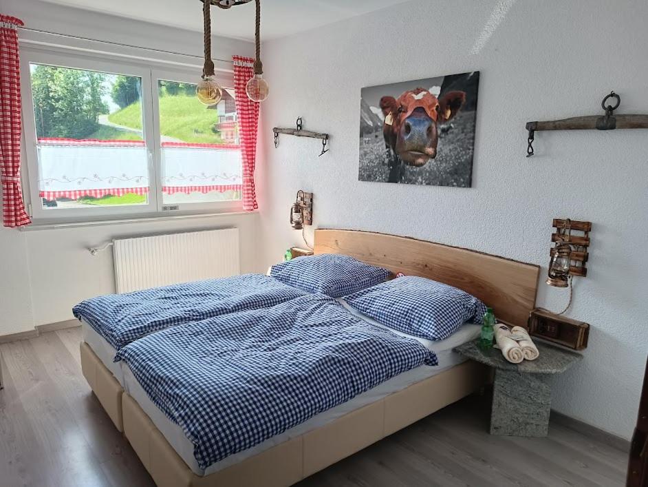 1 dormitorio con 1 cama con una foto de una vaca en la pared en Kuhstall Appartement, en Weiler