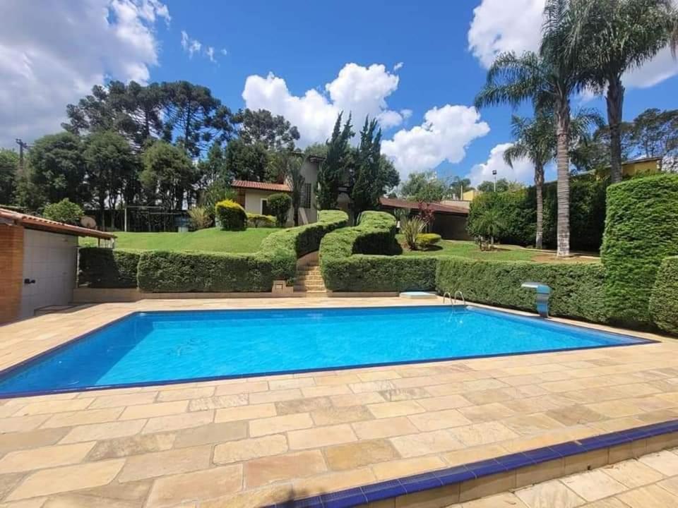 a swimming pool in front of a house with a garden at Quintas Recanto do Sol in Ibiúna