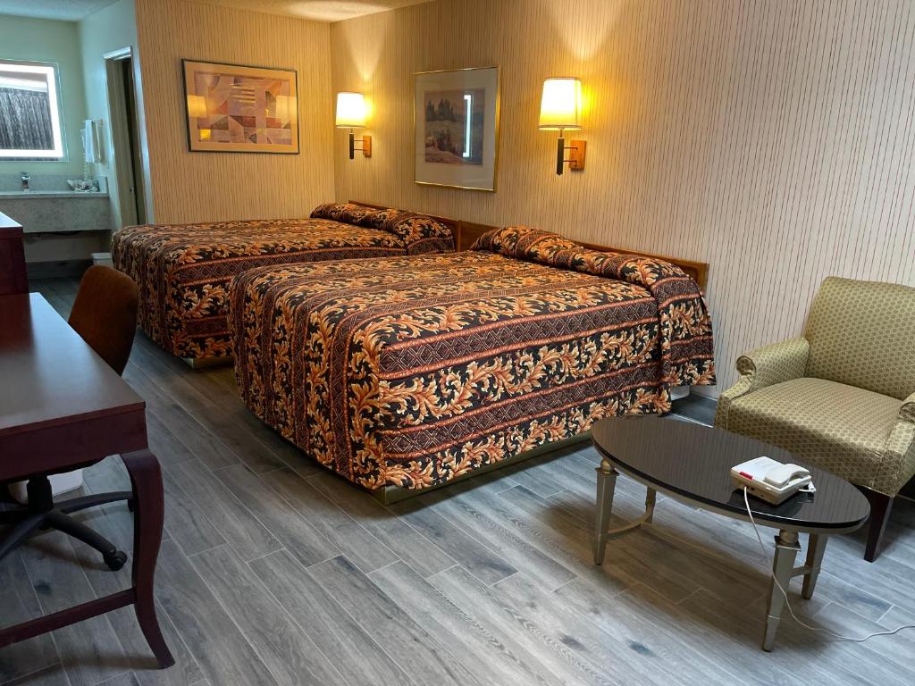 Habitación de hotel con cama y silla en Regency Inn, en Norco