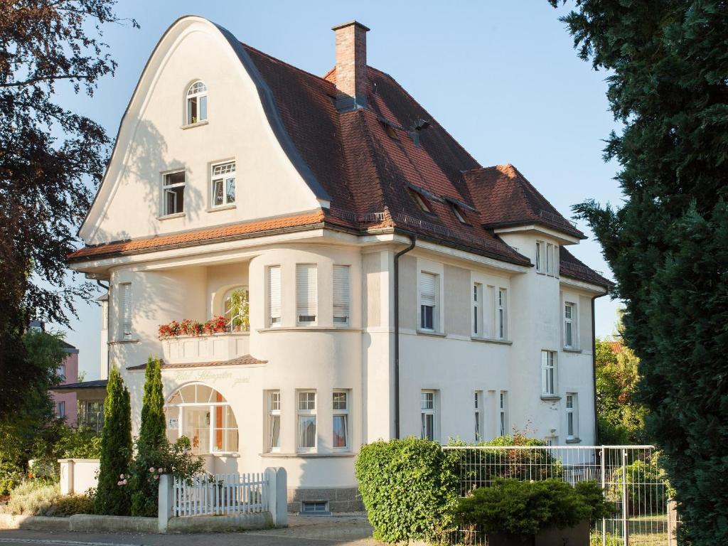 una casa blanca con techo de gambrel en Hotel Schöngarten garni en Lindau