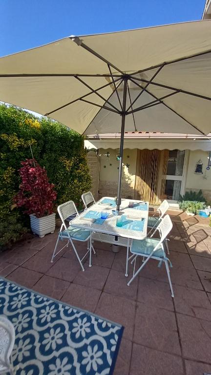 een tafel en stoelen onder een parasol op een patio bij Domus Claudio Garden - Monolocale con giardino privato in Fiumicino