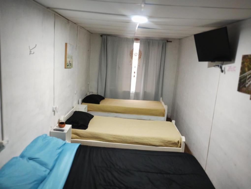Habitación pequeña con 2 camas y TV. en Duplex Olavarría en Olavarría