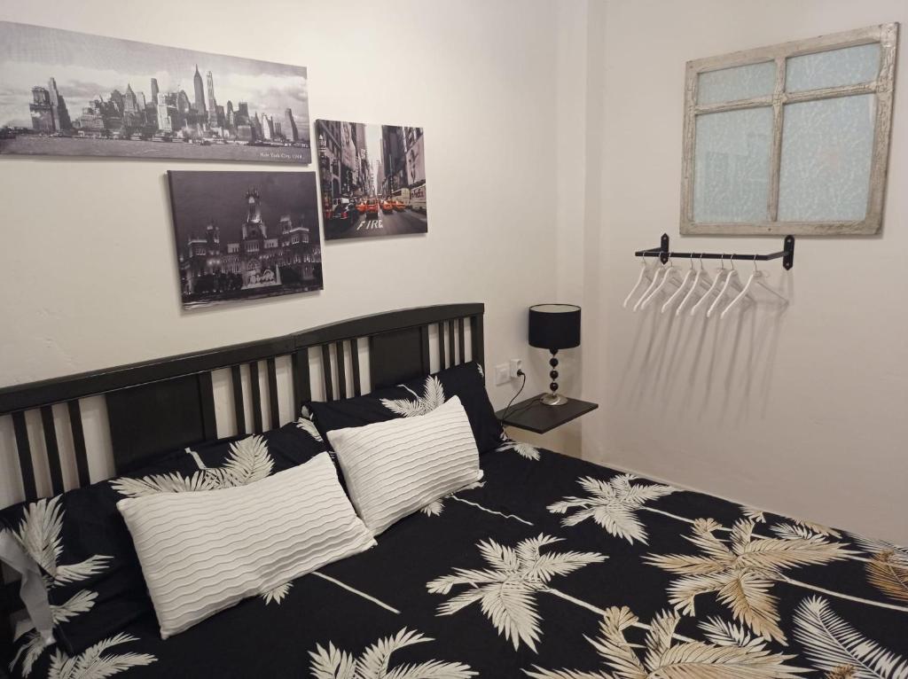 1 dormitorio con cama blanca y negra con almohadas en Apartamentos La Muralla, en Santo Domingo de la Calzada