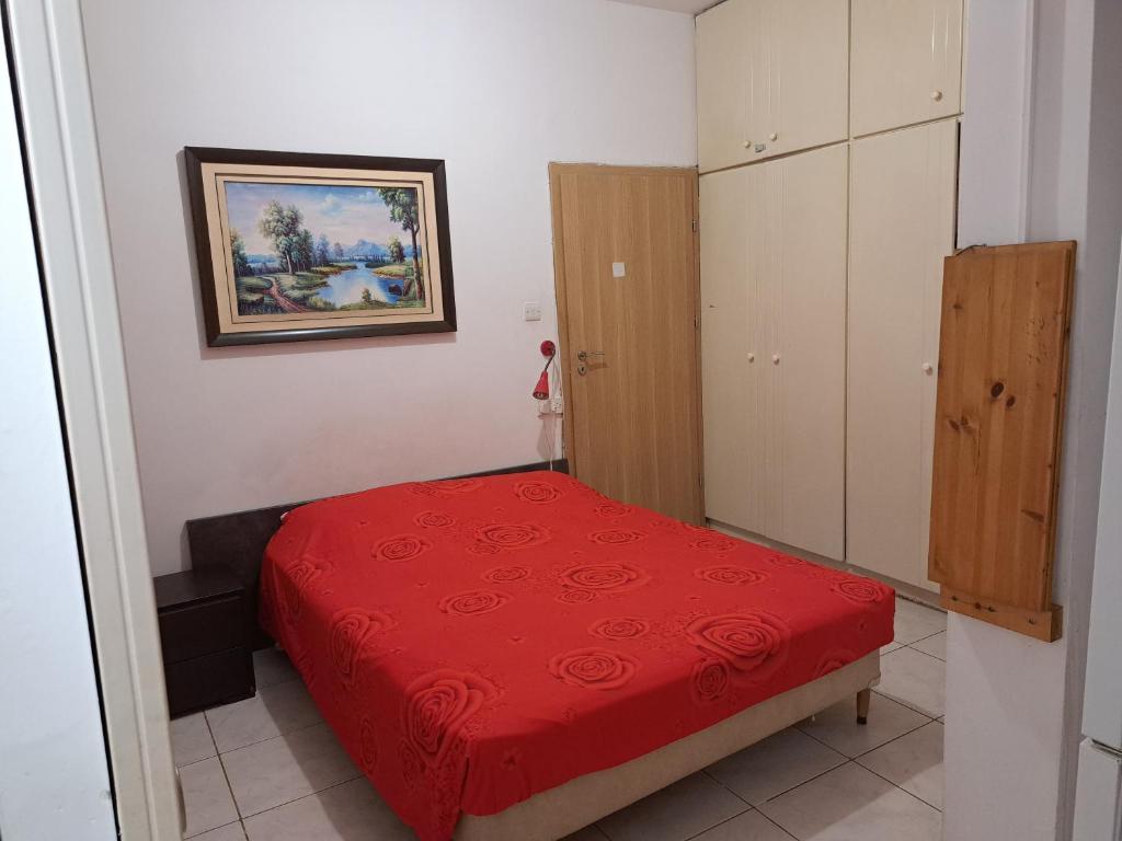 a small bedroom with a red bed and a cabinet at City Large Studio in Limassol