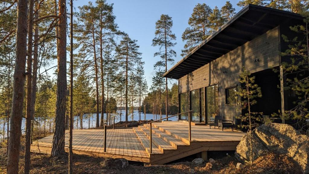 a wooden cabin in the woods with a deck at Lakehouse Juolas in Mäntyharju
