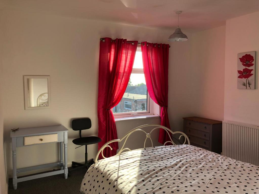 a bedroom with a bed and a window with red curtains at Hilltop Cottage in Renishaw