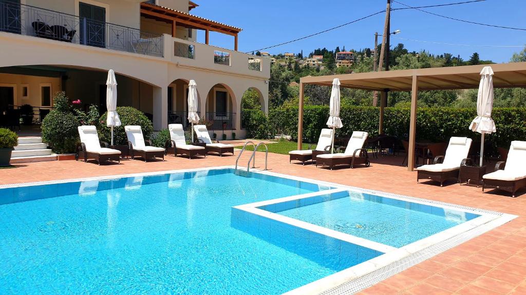 a swimming pool with lounge chairs and a house at Eleana Boutique Hotel & Blue Infinity in Nikiana