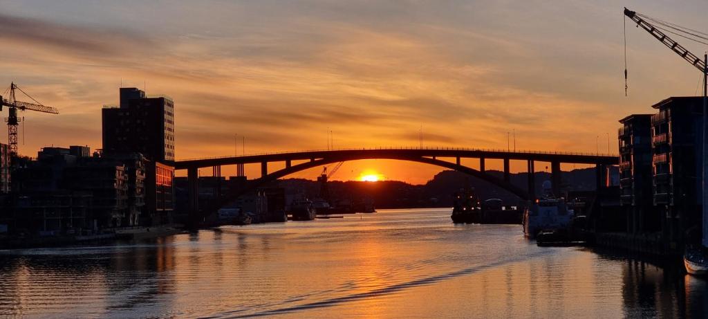 un puente sobre un río con la puesta de sol en el fondo en Byleilighet i sjøkanten m terrasse en Bergen