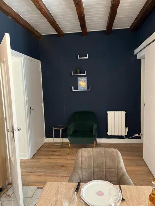 une pièce bleue avec une table et une chaise verte dans l'établissement petite maison à 150m de la plage, à Notre-Dame-de-Monts