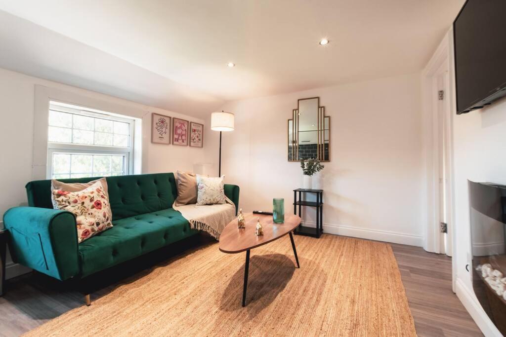 a living room with a green couch and a table at Creedite - 2 Bedroom Flat in Reading