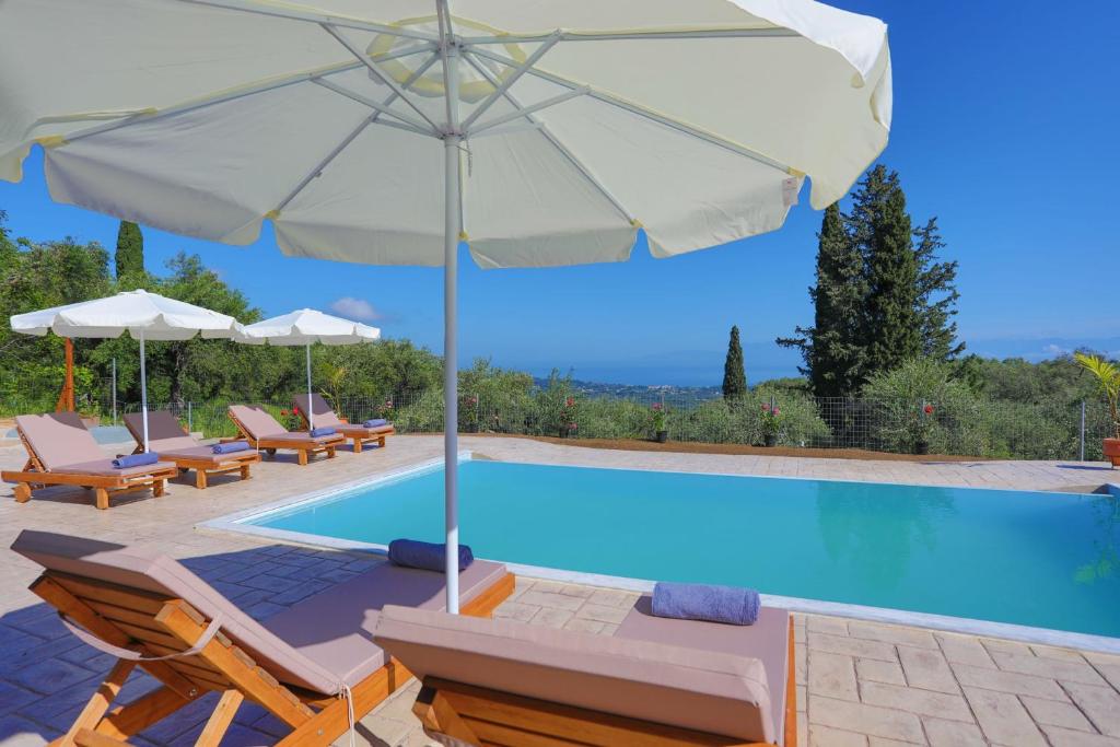 a pool with chairs and umbrellas and a swimming pool at Villa ChrisDina in Nýmfai