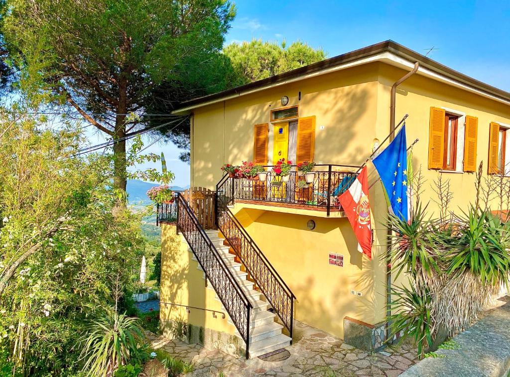 a yellow house with a balcony and a flag at LA GINESTRA B&B in Fosdinovo