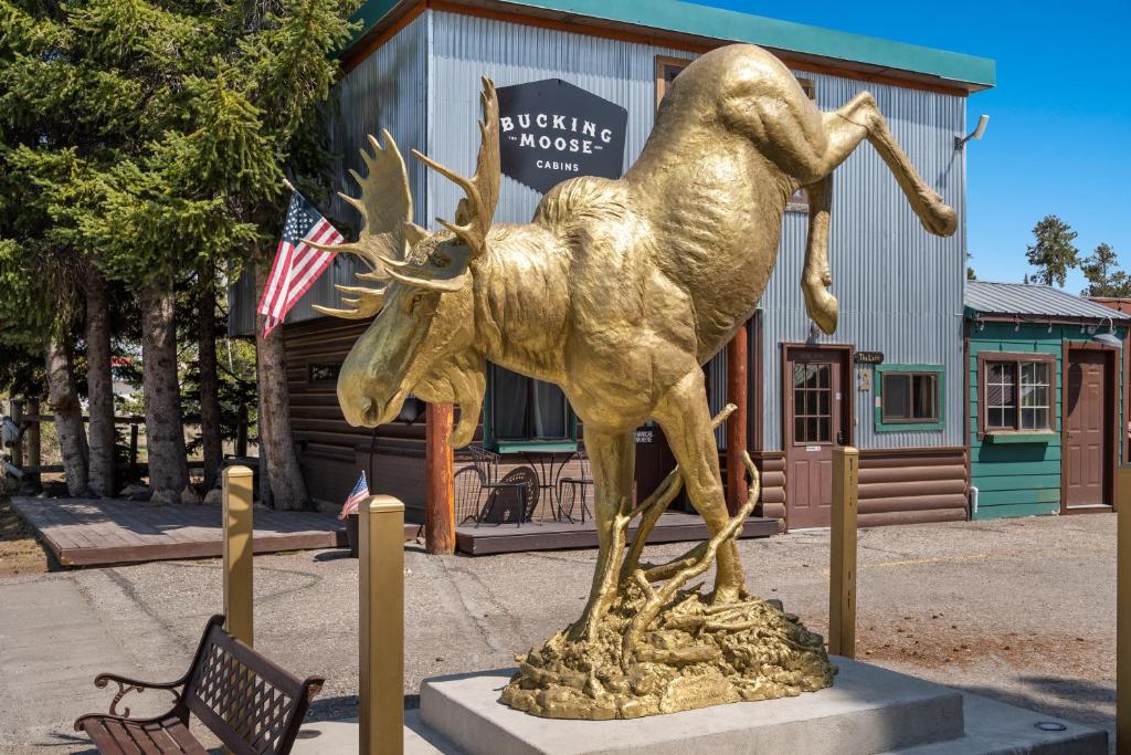 una estatua de oro de un ciervo frente a un edificio en The Bucking Moose, en West Yellowstone