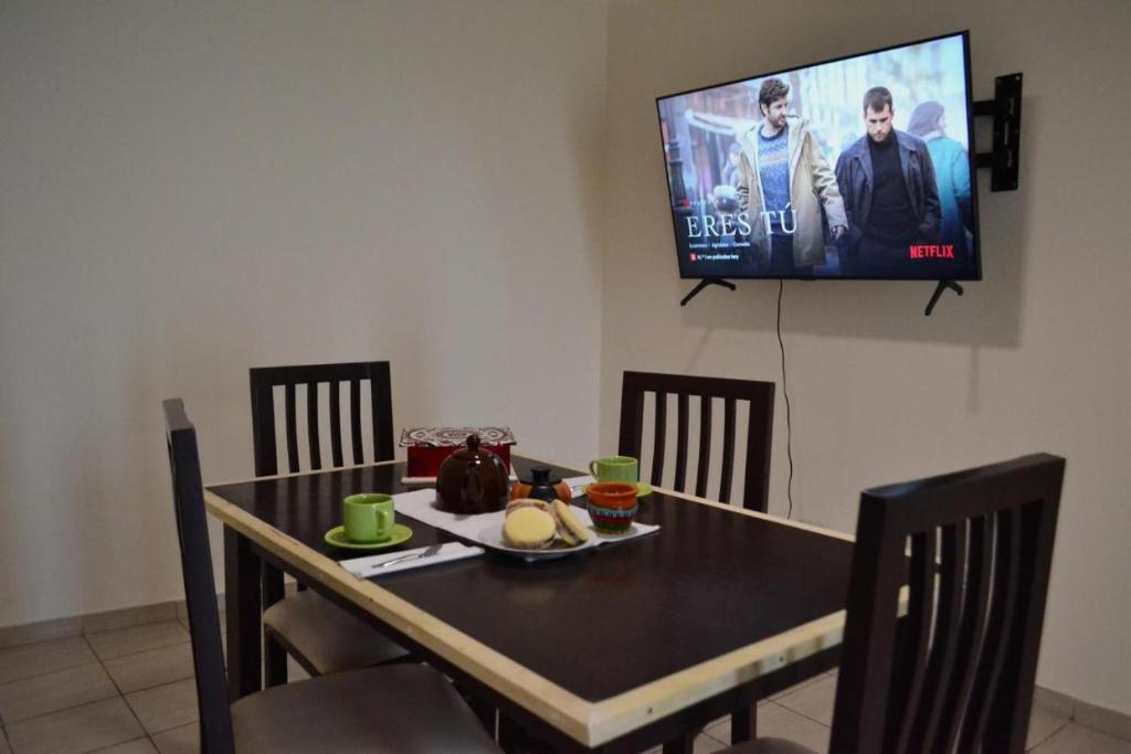 een eettafel met stoelen en een televisie aan de muur bij Ideal Place in Godoy Cruz