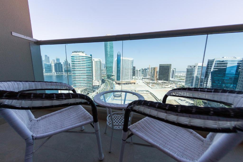 a balcony with chairs and tables and a view of the city at Cosy Studio with Canal Views by Orion Short Stays - 521 Monthly Offer in Dubai