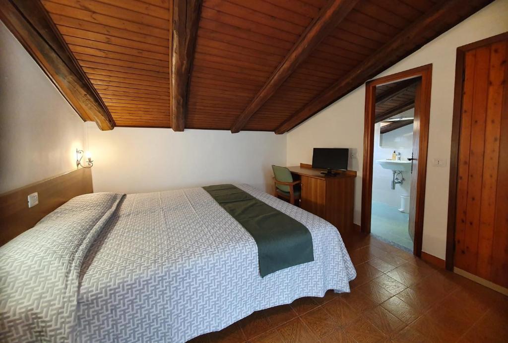 a bedroom with a bed and a desk with a television at Altavilla Albergo meublé in Tirano