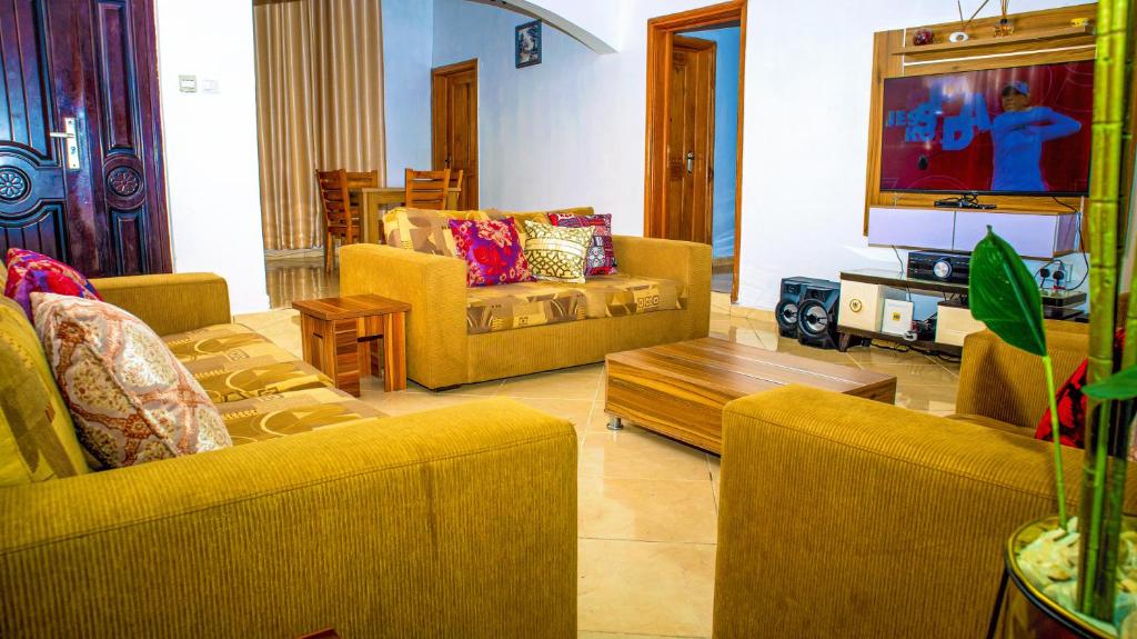 a living room with couches and a flat screen tv at KUNN Apartments in Asaba
