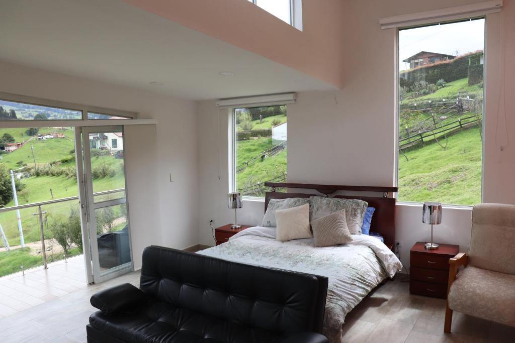 um quarto com uma cama, um sofá e janelas em Glamping en Granja Campo Hermoso em Cogua
