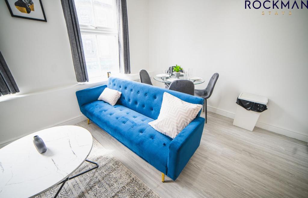 ein Wohnzimmer mit einem blauen Sofa und einem Tisch in der Unterkunft 12B Alexandra Street - Stylish Apartment in the Heart of Southend on Sea by Rockman Stays in Southend-on-Sea