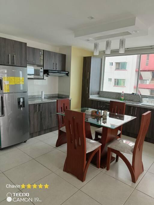 a kitchen with a table and chairs and a refrigerator at Departamento moderno con jacuzzi privado - Porto Vitoria in Tonsupa