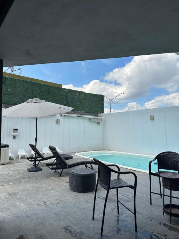 eine Terrasse mit Stühlen, einem Sonnenschirm und einem Pool in der Unterkunft Residencia en Apodaca Nuevo León in Monterrey